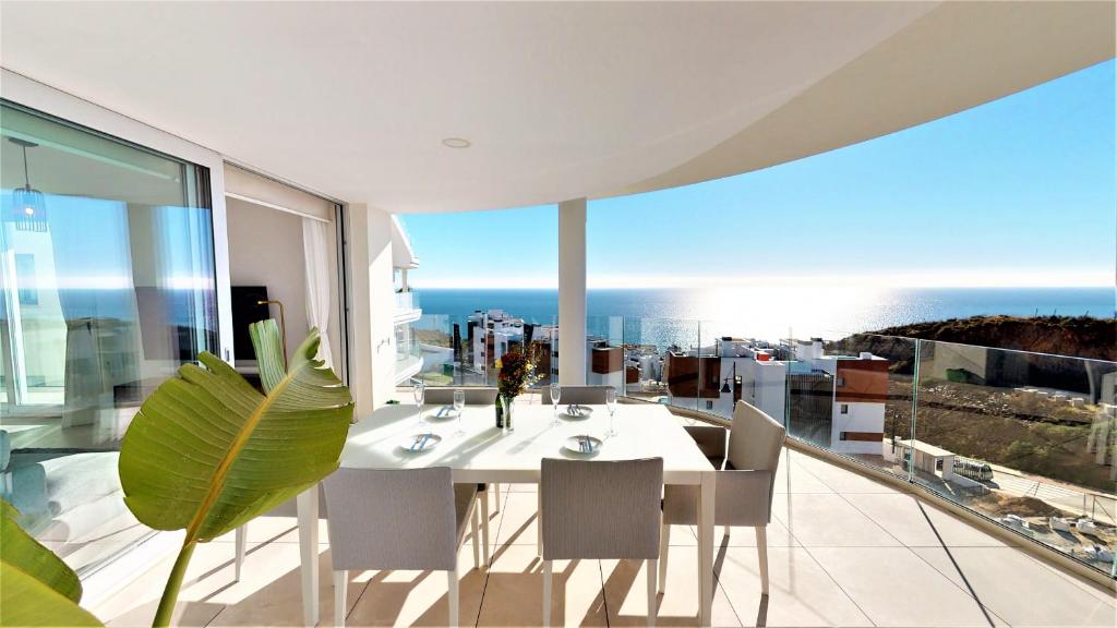 a white dining room with a view of the ocean at Panoramica views superb luxury apartment in Fuengirola