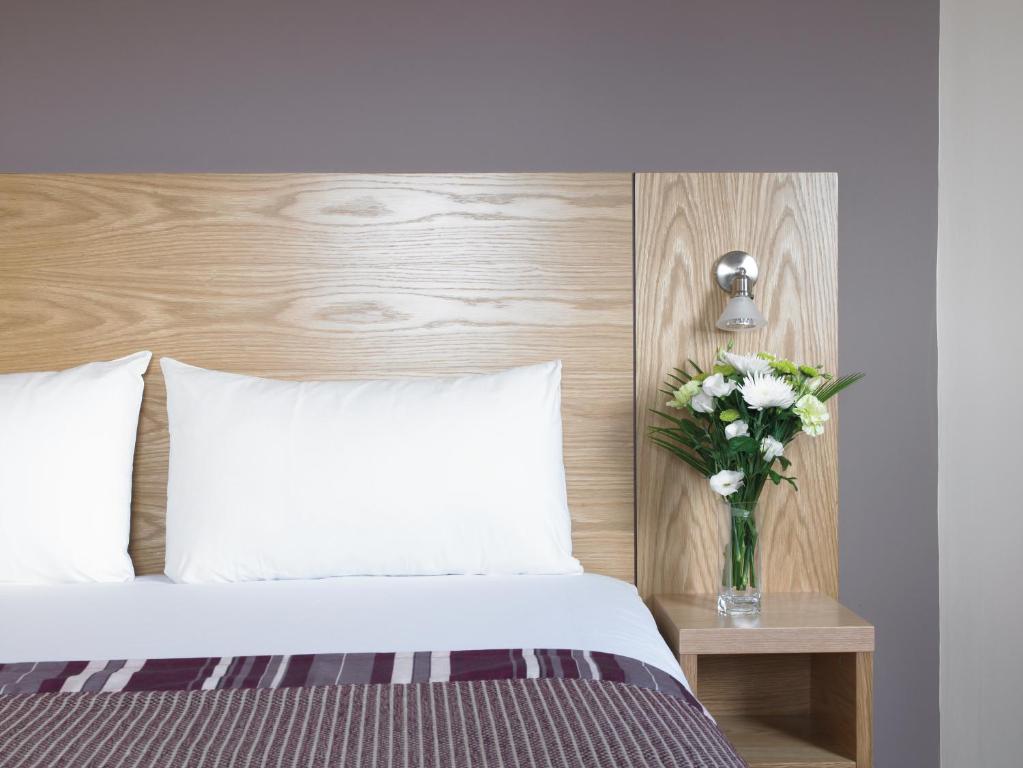 a bedroom with a bed with a vase of flowers on a table at Leonardo Hotel Aberdeen in Aberdeen