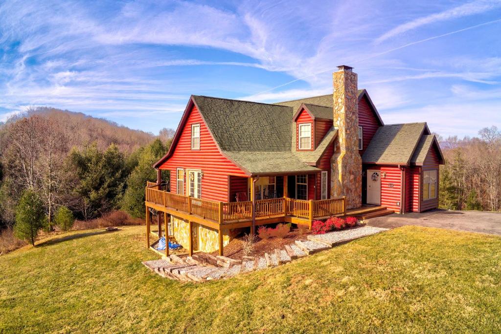 ein rotes Haus mit einer Terrasse auf einem Rasen in der Unterkunft Spacious Mountain-View Manor with Easy River Access! in Piney Creek