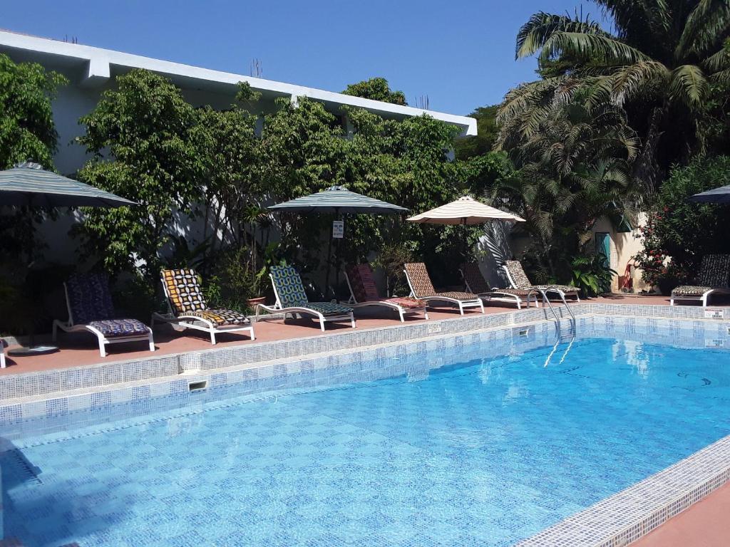 a swimming pool with lounge chairs and umbrellas next to at Riyan Apartment in Kololi