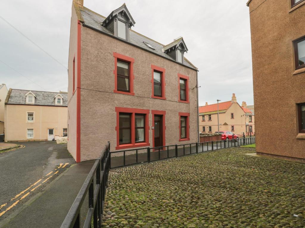 a brick building with red windows on a street at Harbour Retreat in Eyemouth