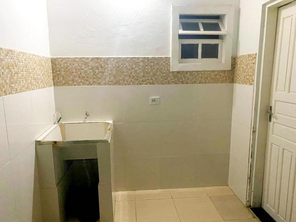 ein kleines Badezimmer mit Waschbecken und Fenster in der Unterkunft Peruibe centro mar 944 in Peruíbe