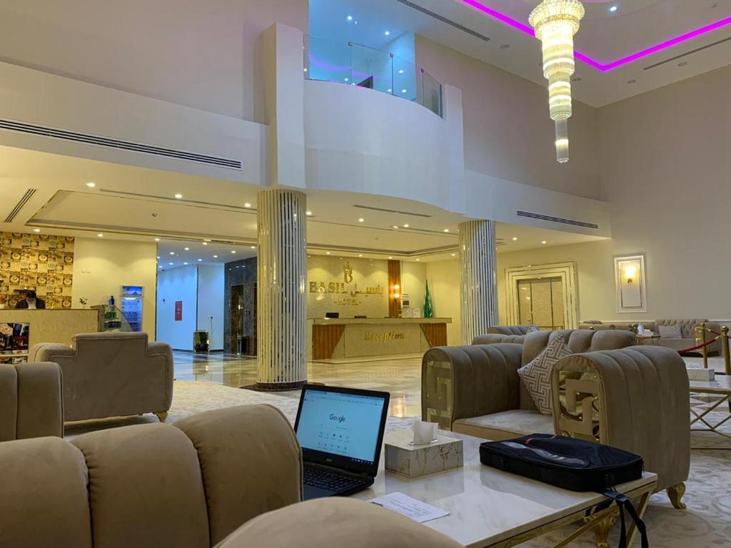 un vestíbulo con sofás y un ordenador portátil sobre una mesa en فندق بــــاســــيل, en Hafr Al Batin