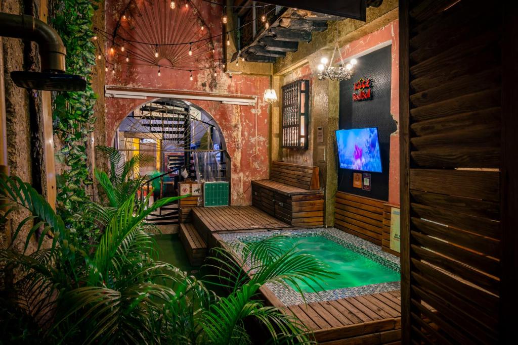 an indoor pool in a room with a tv and plants at The Clock Hostel & Suites in Cartagena de Indias