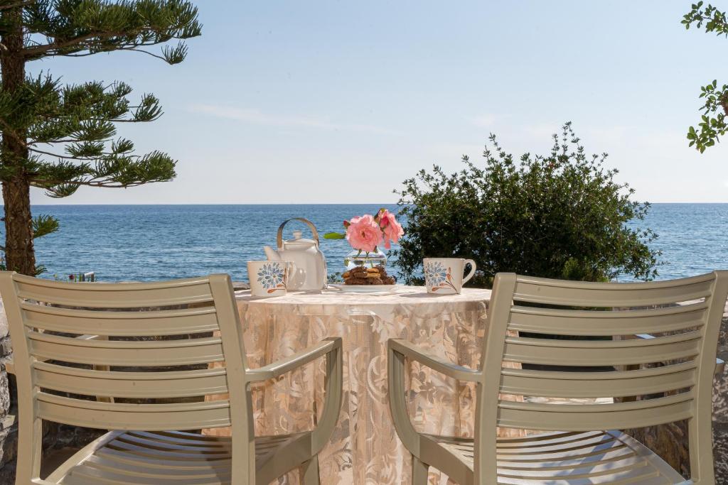 a table with two chairs with the ocean in the background at Villa Plori in Makry Gialos