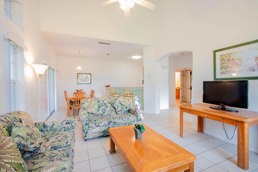 ein Wohnzimmer mit einem Sofa, einem TV und einem Tisch in der Unterkunft Berkley Lake Townhomes in Kissimmee