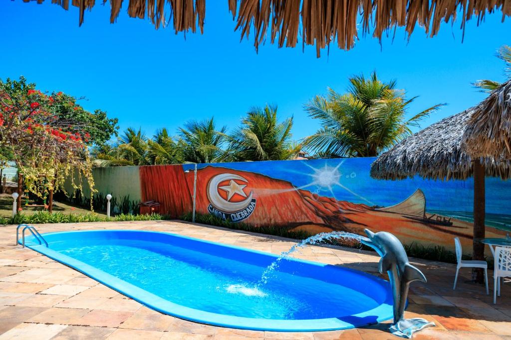 a swimming pool with a fountain in front of a wall at Pousada Iguana in Canoa Quebrada