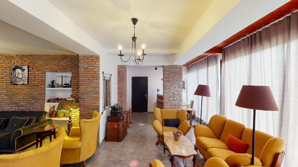 a living room with yellow furniture and a brick wall at Boutique Hotel Shale in Bakuriani
