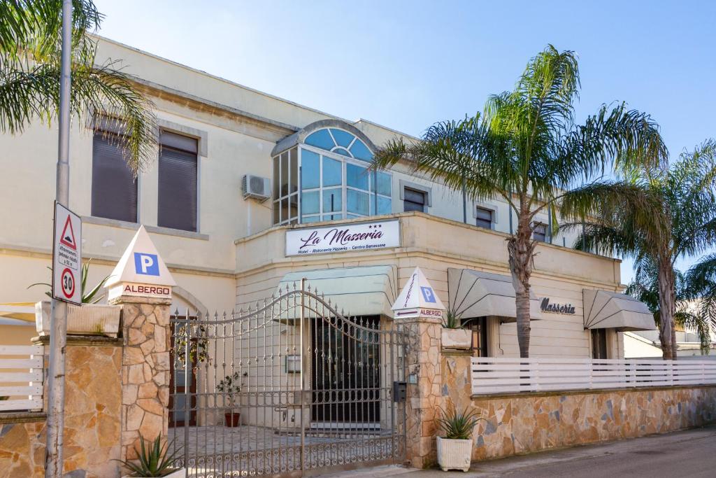 un edificio con una palmera delante de él en La Masseria Hotel Ristorante Centro Benessere, en Cocumola