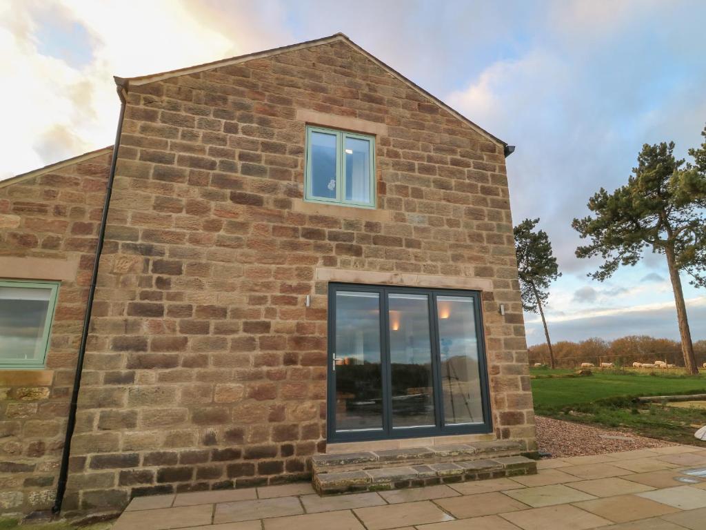 Una casa de ladrillo con una ventana en el costado. en Ploughman's Rigg en Harrogate