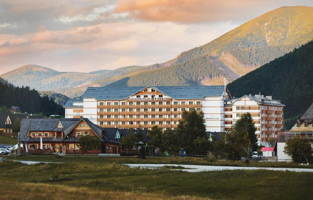 un gran edificio con montañas en el fondo en Apartmány RESIDENCE Donovaly, en Donovaly