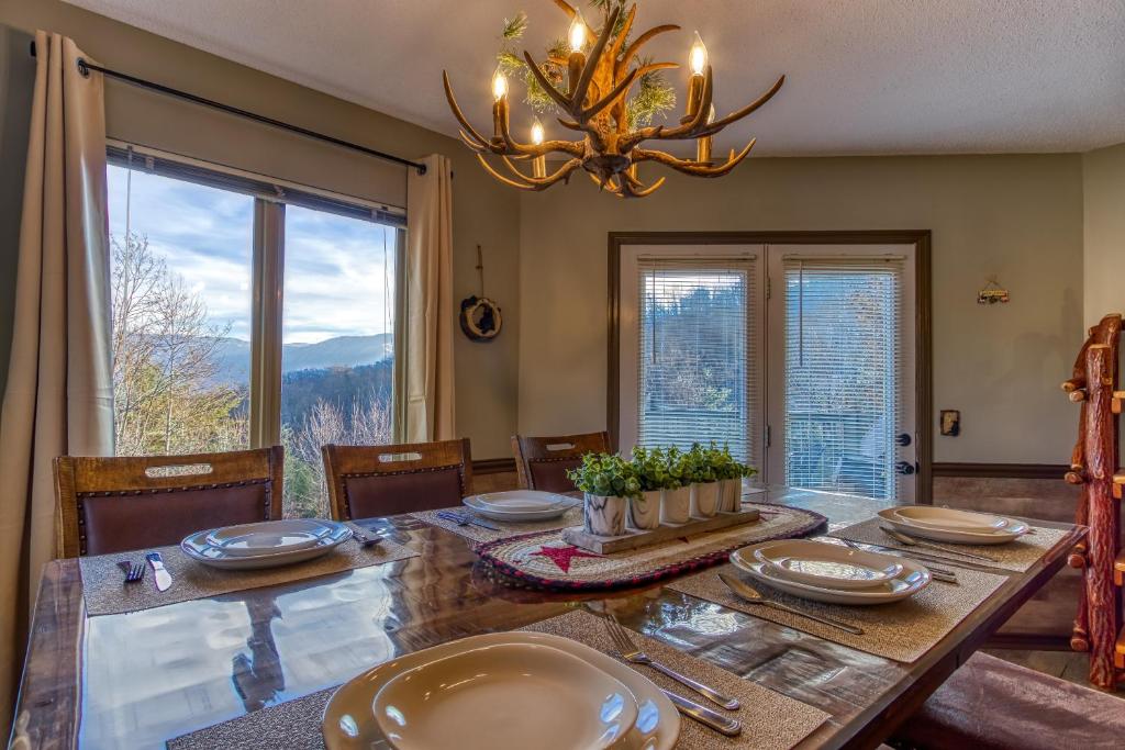 a dining room with a table and a chandelier at 3 Decks, Mtn Views! Tree Tops by HoneyBearCabins - Luxury Rain Showers, 3 King suites, XL HotTub, Fireplace, Bear Sightings in Gatlinburg
