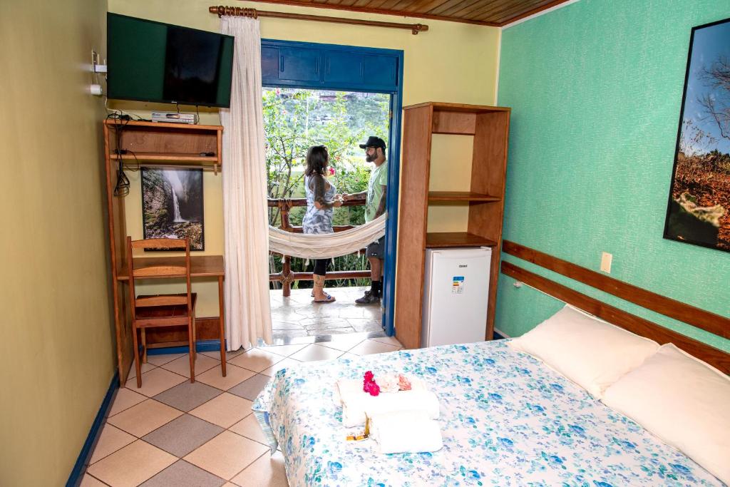 ein Schlafzimmer mit einem Mann und einer Frau, die vor der Tür stehen in der Unterkunft Pousada Recanto da Chapada in Mucugê
