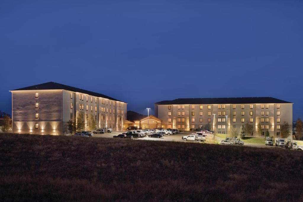 dois edifícios num parque de estacionamento à noite em Bakken Airport XWA Hotel & Studios em Williston