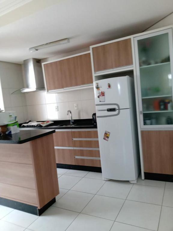 a kitchen with a white refrigerator and wooden cabinets at Apartamento Temporada Florianópolis in Florianópolis