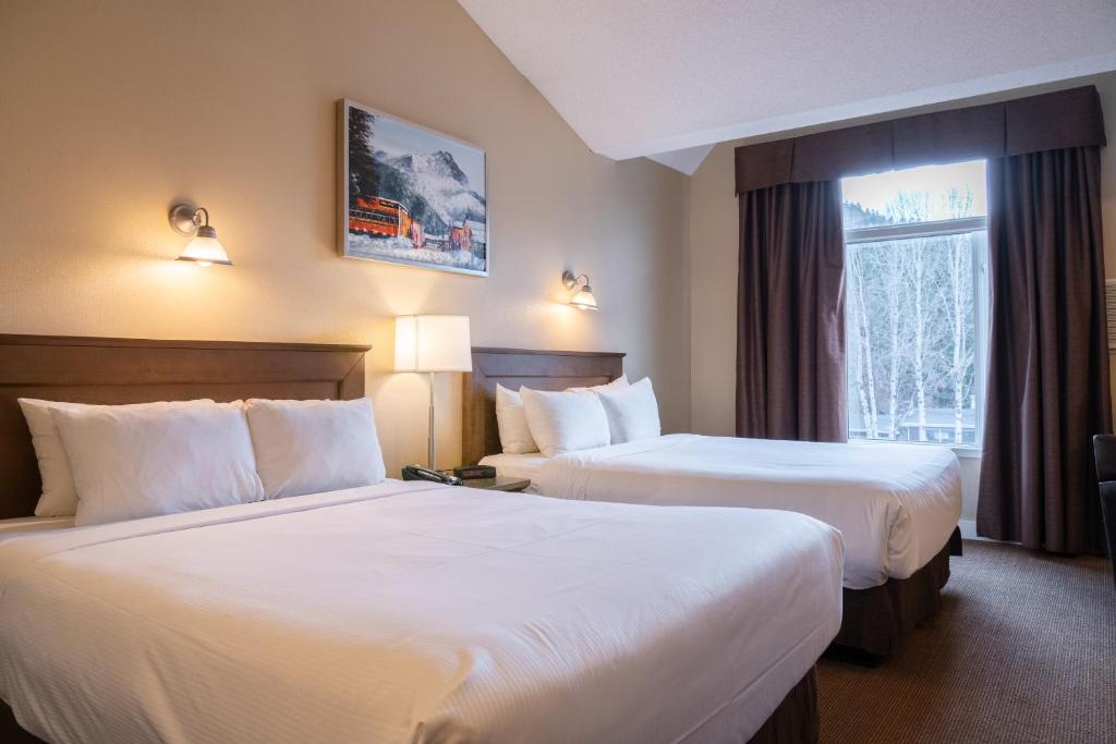 
a hotel room with two beds and two lamps at Irwin's Mountain Inn in Banff
