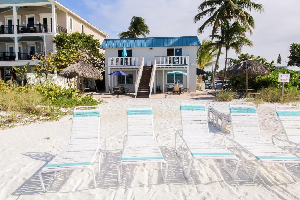 a group of beach chairs on the sand in front of a house at Anna Maria Island Inn in Bradenton Beach