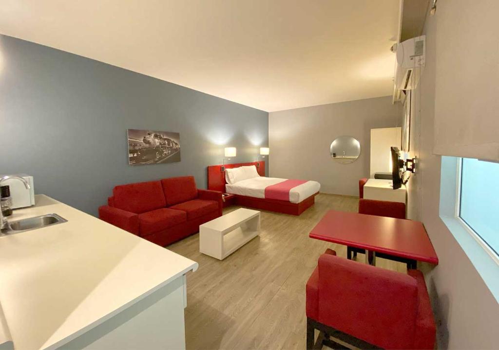 uma pequena sala de estar com um sofá vermelho e uma cama em Hotel MX forum buenavista em Cidade do México