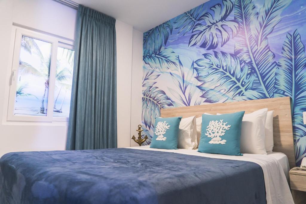 1 dormitorio con cama azul y papel pintado tropical en Sea Colors Hotel, en San Andrés