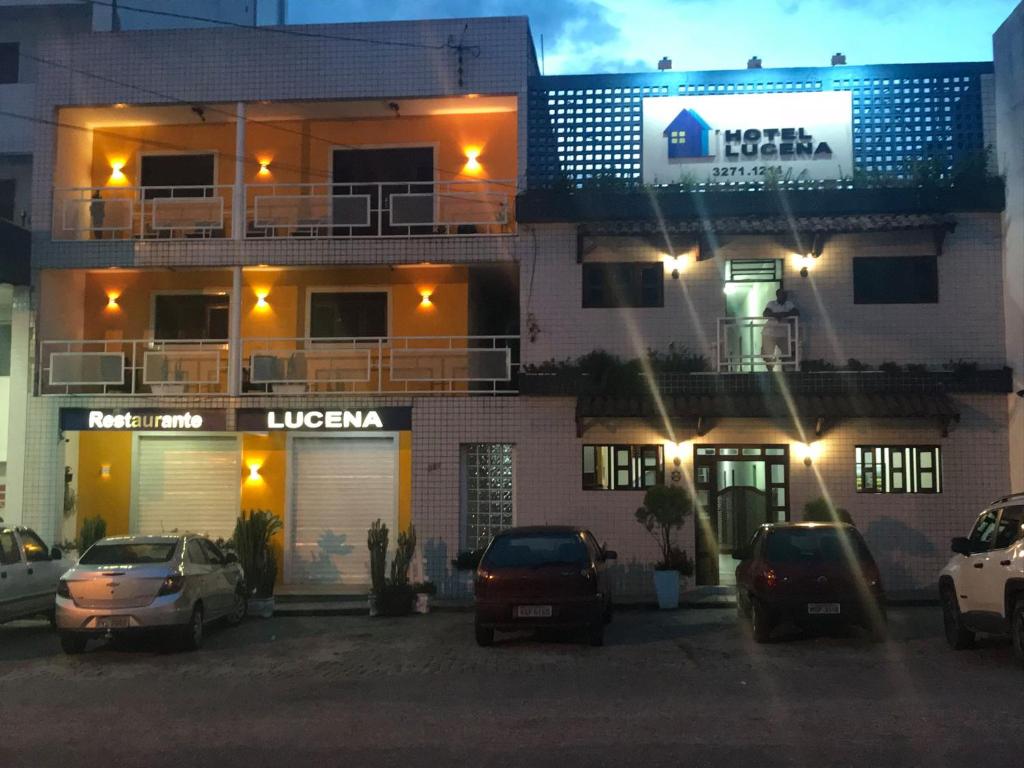un bâtiment avec des voitures garées dans un parking la nuit dans l'établissement Hotel Lucena, à Guarabira