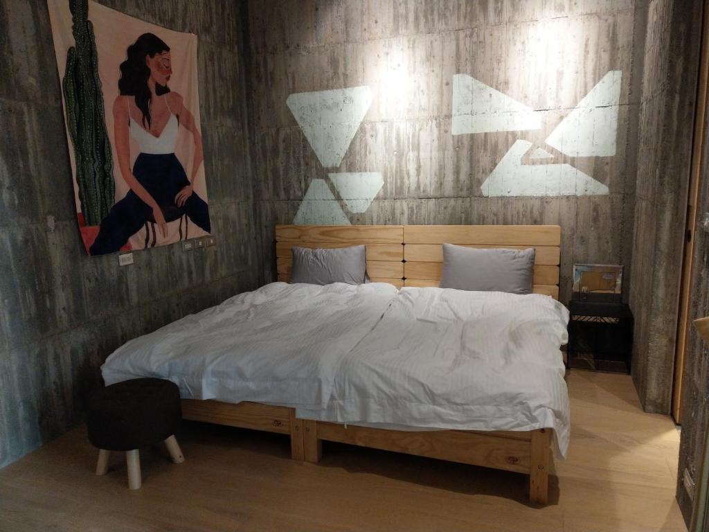 a bedroom with a bed with a painting on the wall at 350 Lodge in Taitung City