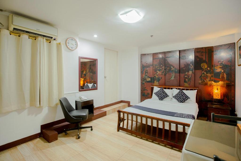 a bedroom with a bed and a desk and a chair at Newgrange Condotel in Manila