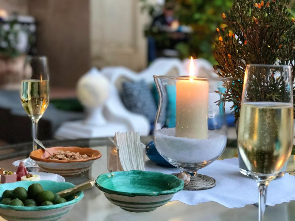 una candela seduta su un tavolo con piatti e bicchieri da vino di 2 bedrooms house with furnished terrace at Noto 6 km away from the beach a Noto