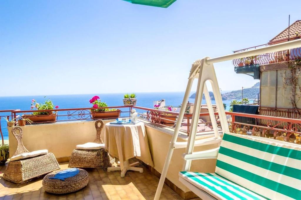 einen Balkon mit einer Leiter, einem Tisch und Stühlen in der Unterkunft 2 bedrooms house at Letojanni 500 m away from the beach with sea view furnished terrace and wifi in Letojanni