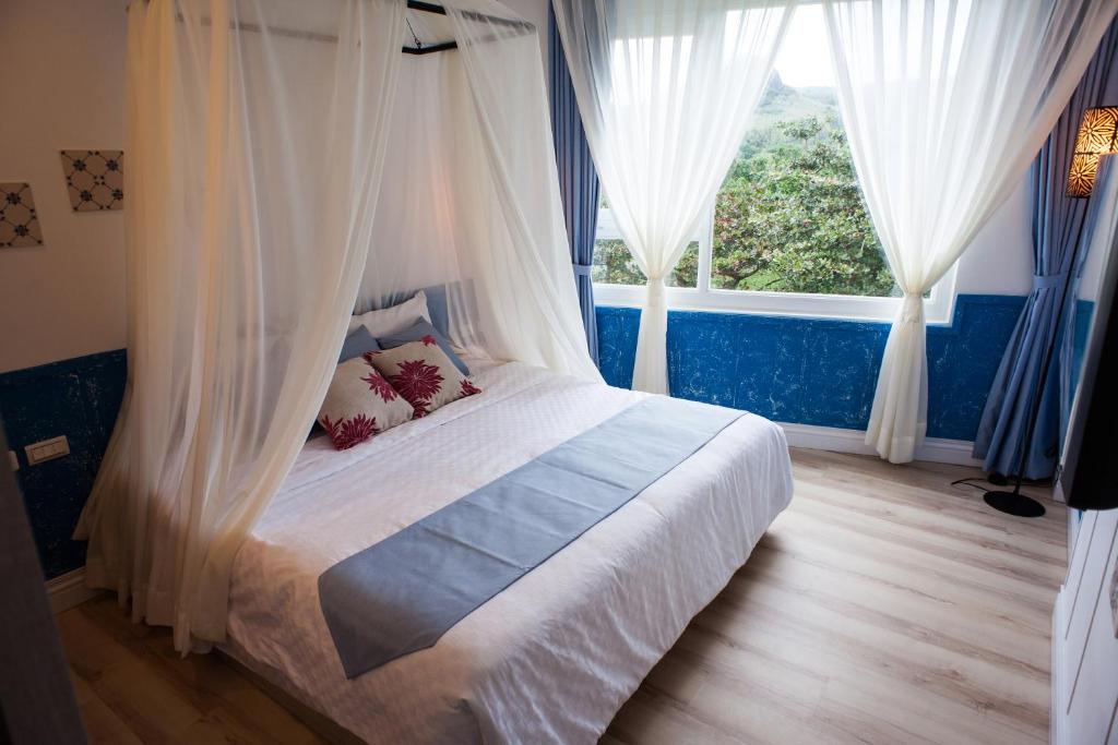 1 dormitorio con 1 cama con cortinas y ventana en Ho Huan B & B, en Kenting