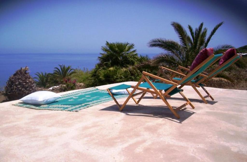 twee ligstoelen op het zand naast een zwembad bij Studio with sea view and furnished garden at Pantelleria 1 km away from the beach in Tracino