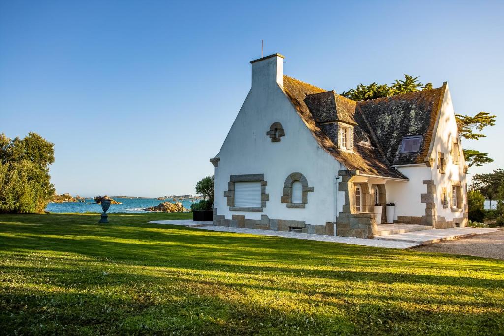 a person holding an umbrella in front of a house at Villa charmante à Roscoff avec vue sur la mer in Roscoff
