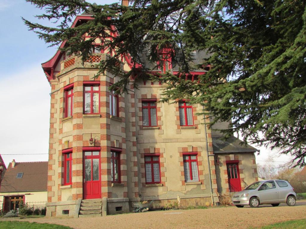 un edificio con ventanas rojas y un coche aparcado delante en Chateau Lezat - Chambres d'Hotes et Table d'Hotes, en La Souterraine