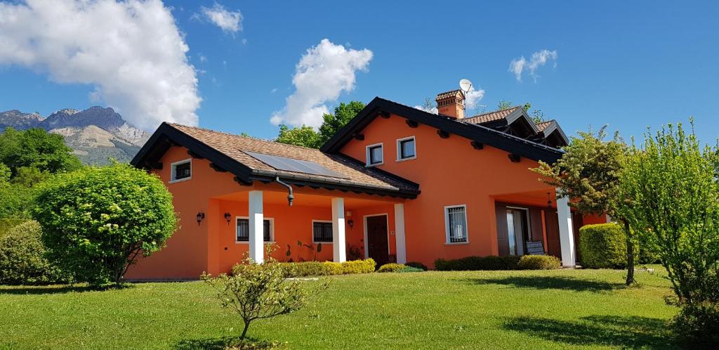 a orange house with a grass yard in front of it at Bed & Breakfast Paradiso in Cesiomaggiore