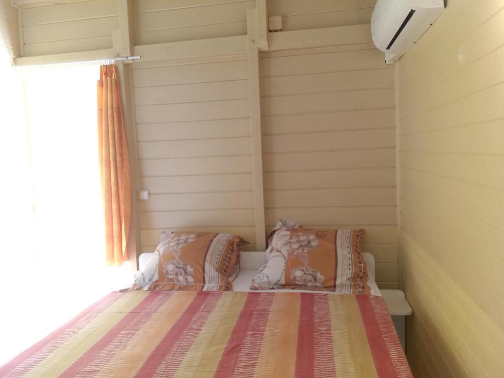 uma cama com duas almofadas num pequeno quarto em Appartement de 2 chambres a Sainte Rose a 300 m de la plage avec vue sur la mer jardin clos et wifi em Sainte-Rose