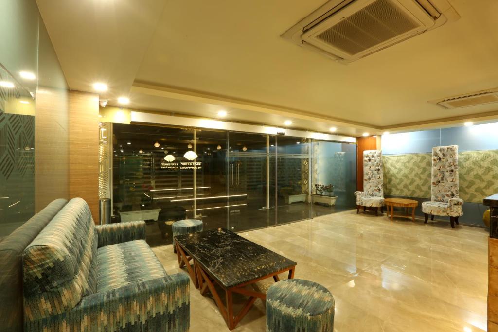 a lobby with a couch and a table and chairs at Hotel Omega - Gurgaon Central in Gurgaon