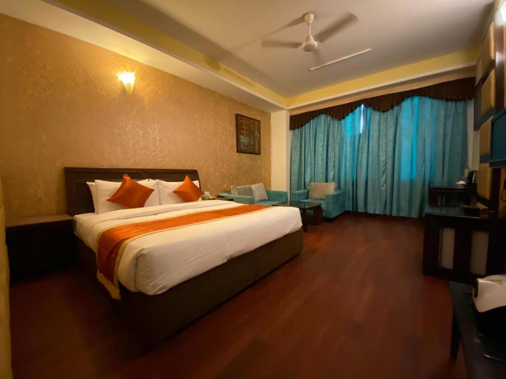 um quarto com uma cama grande e cortinas azuis em Hotel The Pearl Industrial Area Phase-2 em Chandīgarh