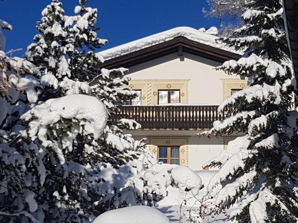 uma casa coberta de neve com árvores no primeiro plano em Tgampi saura 395 Rü em Lenz