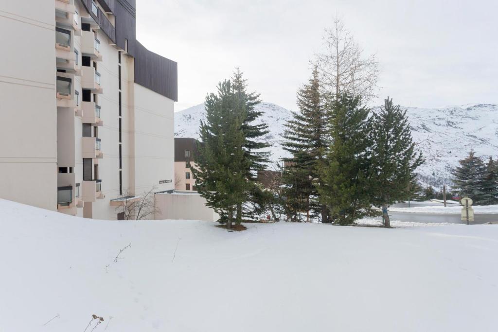 a snow covered street with trees and a building at Le Chamois - A 20m des pistes ! in Saint-Martin-de-Belleville