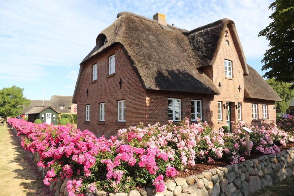 a house with a thatched roof and pink flowers at Lunhues Lucia in Dunsum