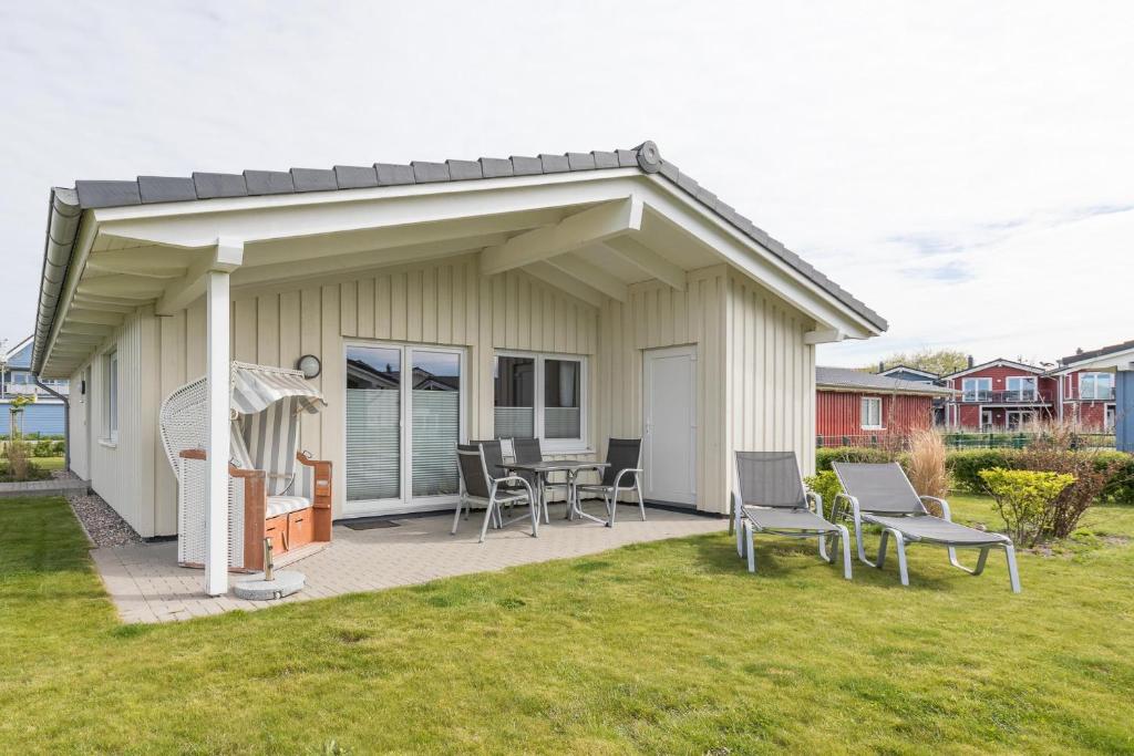 Cette maison dispose d'une terrasse avec des chaises et une table. dans l'établissement Ferienhaus Langeneß, à Dagebüll