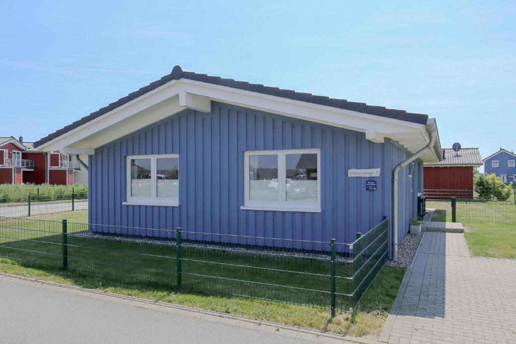 a blue building with two windows on a street at Ferienhaus Norderoog in Dagebüll