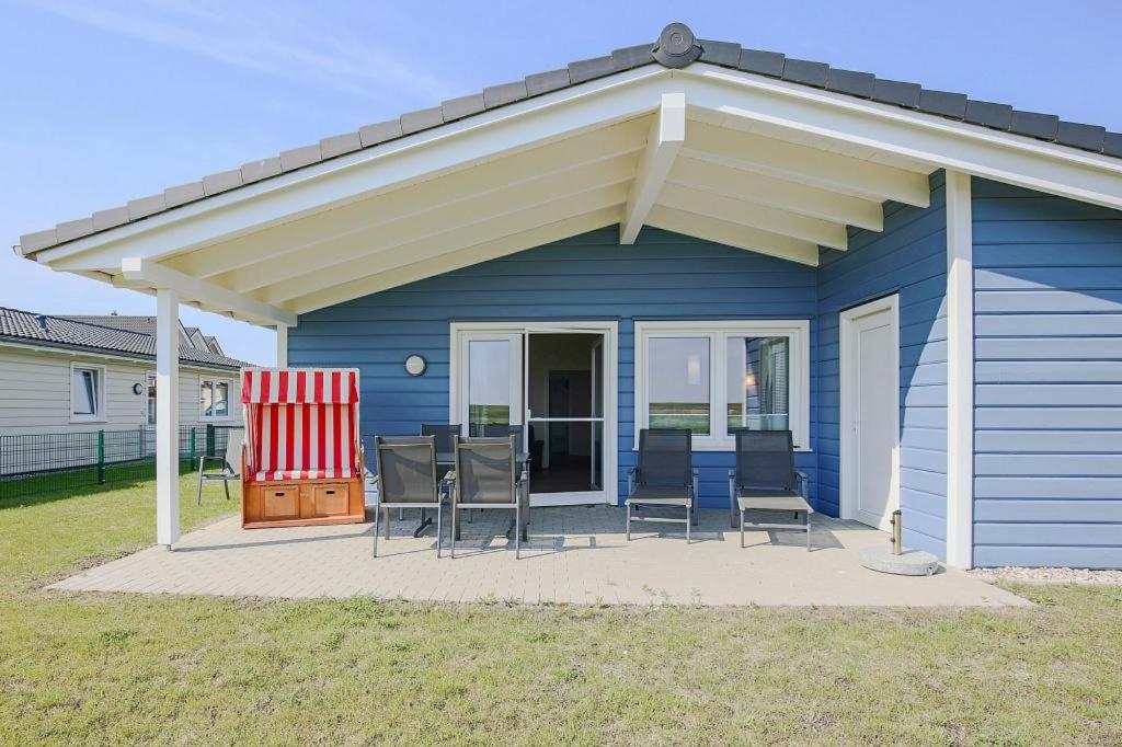 ein blaues Haus mit Markise und Stühlen auf einer Terrasse in der Unterkunft Ferienhaus Herzmuschel in Dagebüll