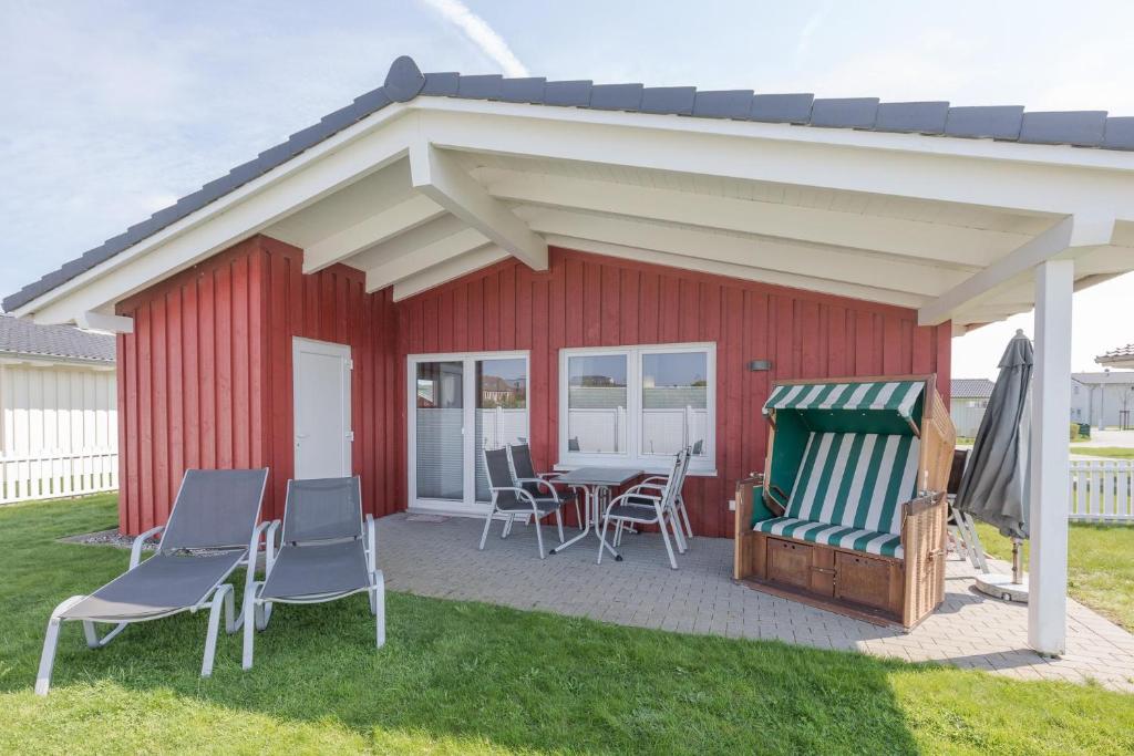 a red shed with chairs and a table and awning at Ferienhaus Strandflieder in Dagebüll