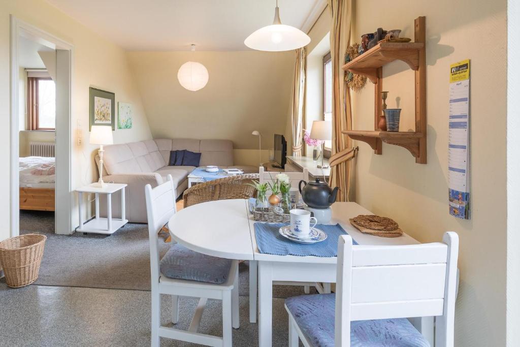 a dining room and living room with a white table and chairs at Ferienwohnung in Borgsum (oben rechts) in Borgsum