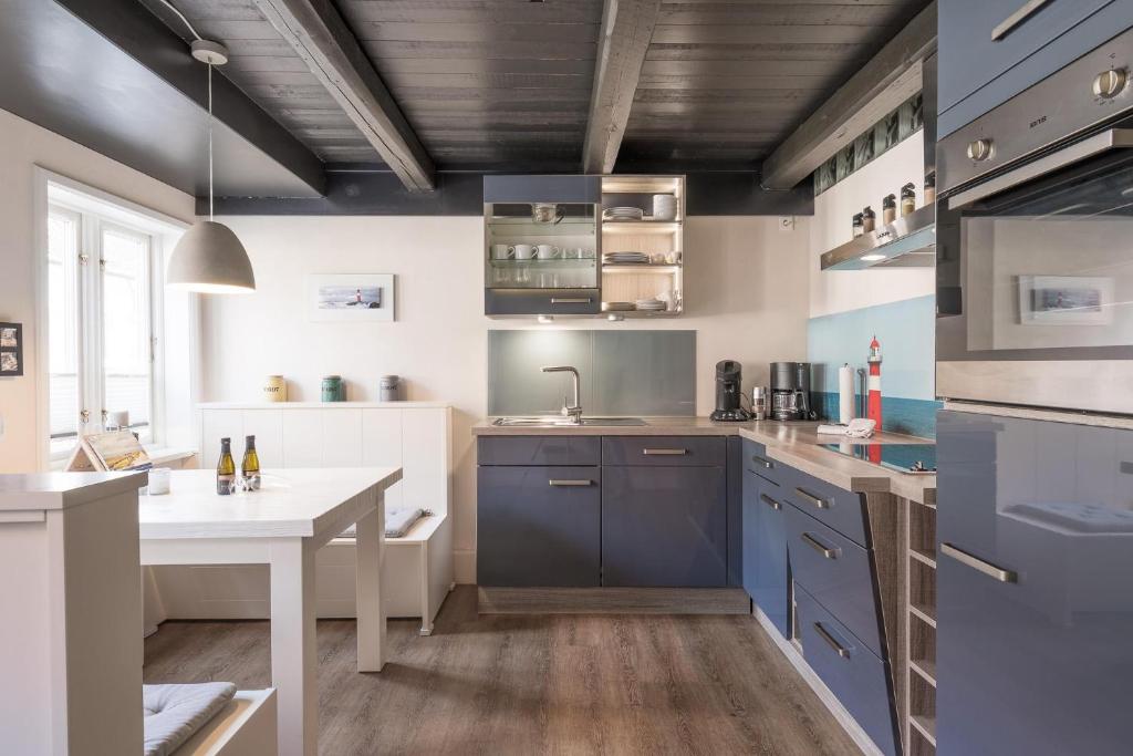 eine Küche mit blauen Schränken und einem weißen Tisch in der Unterkunft Matthis Skipperhuus in Husum