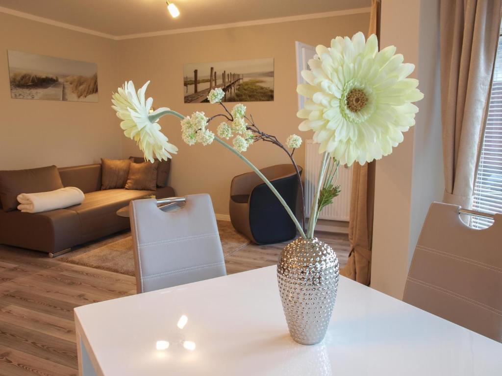eine Vase mit Blumen auf einem Tisch im Wohnzimmer in der Unterkunft Apartment Godewind in Dagebüll