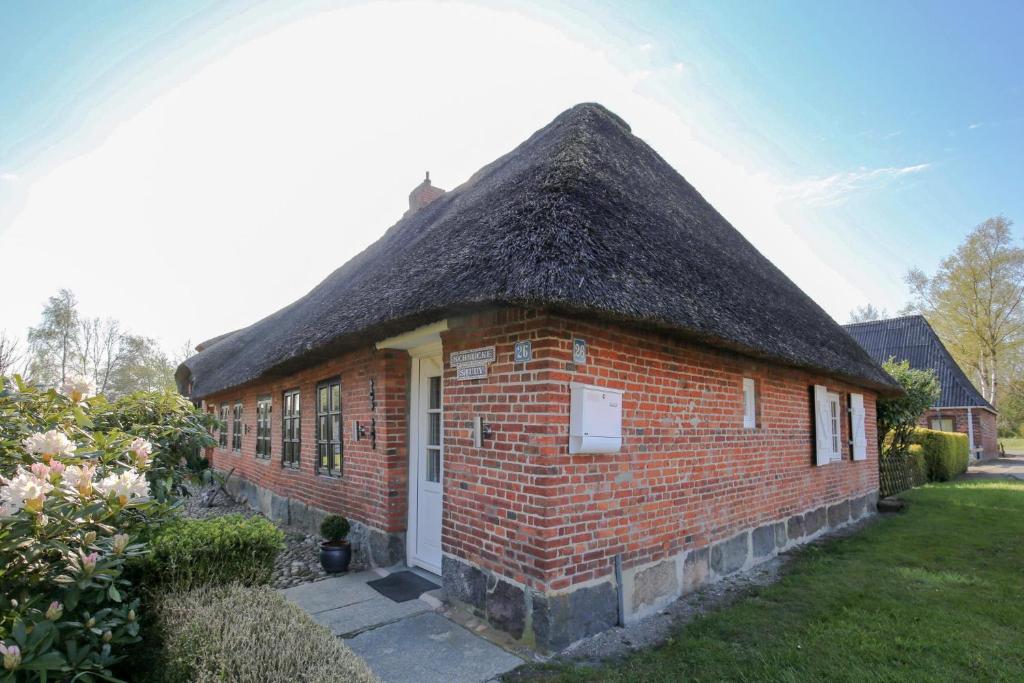a small brick building with a thatched roof at Schmucke Stuuv in Rantrum