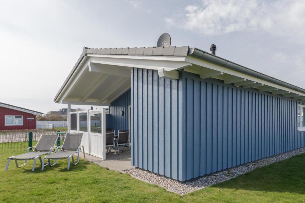 a blue building with a roof and two chairs at Ferienhaus Amrum in Dagebüll