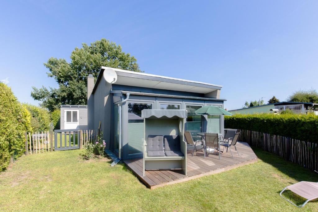 a tiny house with a deck in a yard at Ferienhaus vor Rügen in Sundhagen