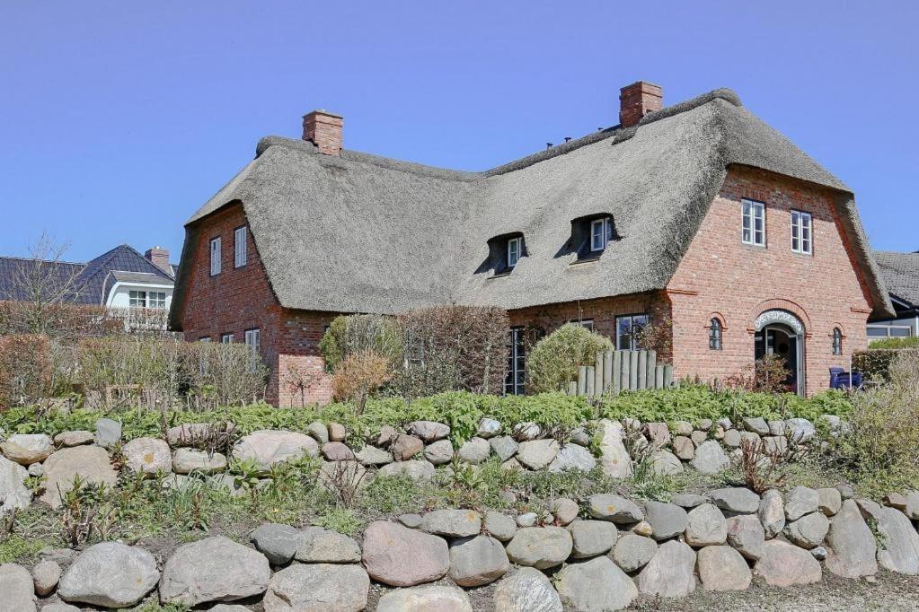 una vieja casa de ladrillo con una valla de piedra delante de ella en Reethus Ulla en Husum